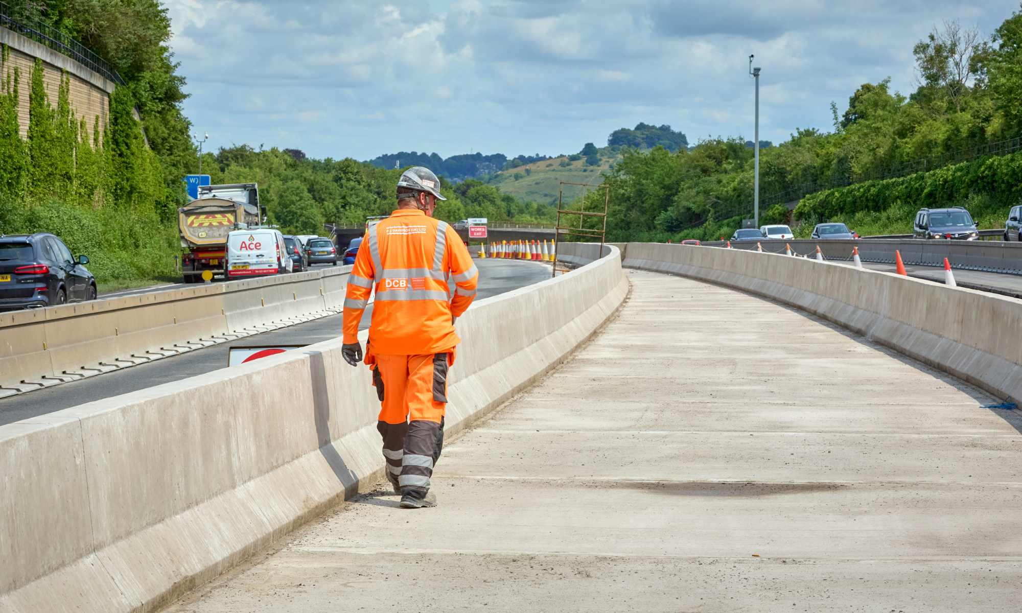 Man in orange PPE, walking down a closed off section of a road
